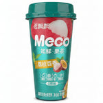 A hand holding a can of Meco 如鲜果茶 (grapefruit tea) on a wooden desk with office items in the background.