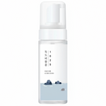 A frosted glass pump bottle with a white cap and a minimalist label featuring a light blue water design with dark blue rocks and vertical Korean text reading '1025'.