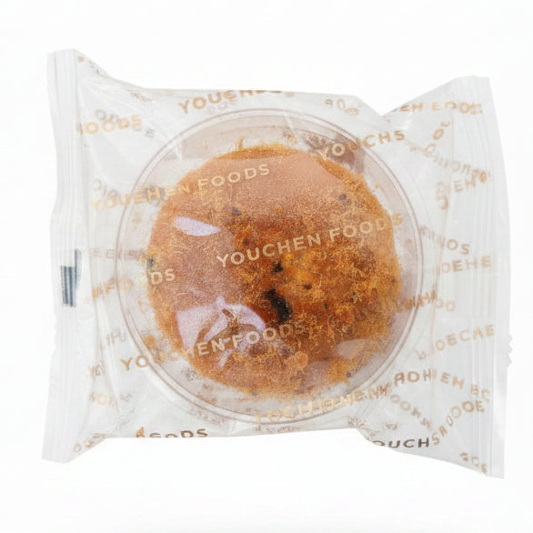 Hand holding a packaged cookie with 'Youcher Foods' branding in a store setting.